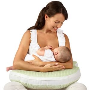 A mother smiling down at her infant baby while breastfeeding, using it as the nursing pillow guide suggest to position.