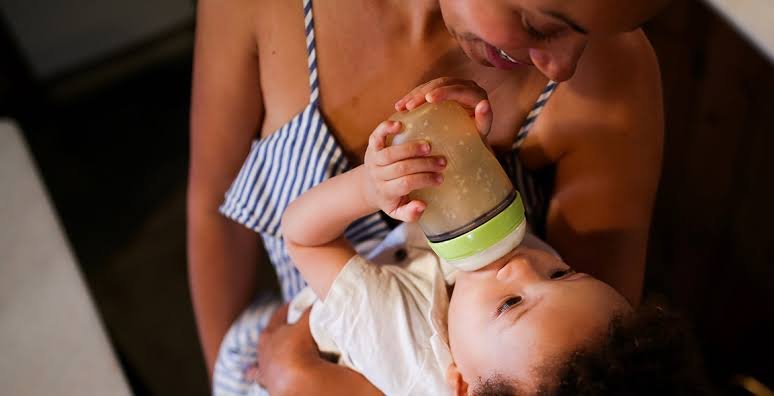A mom feeding her baby illustrating how much should a newborn eat guide.